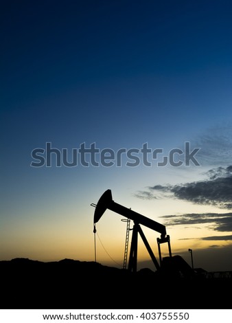 Sunset and silhouette of crude oil pump in the oilfield
