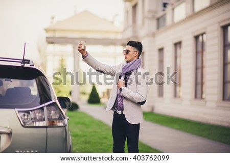 Stylish man near the car makes the photo with joy
