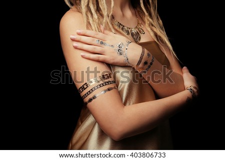 Young blonde girl with golden and silver flash tattoo on black background