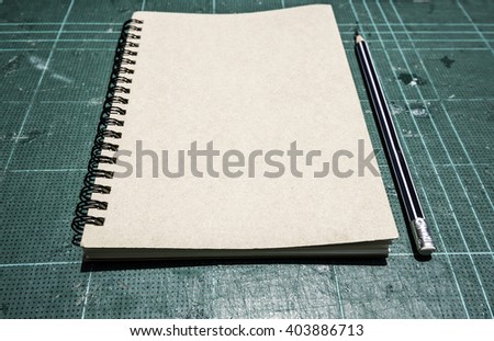 Notebook with pencil, selective focus on old cutting mat