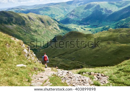 A hiker walking in the English Lake District, UK. Royalty-Free Stock Photo #403899898
