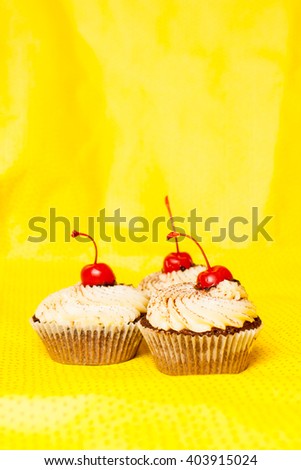 Sweet muffins with cherry on yellow background
