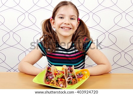 happy little girl with tacos on plate