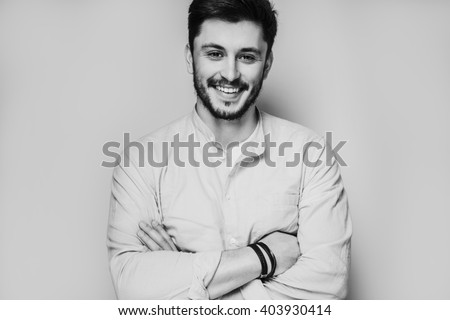 black and white portrait of handsome smiling man isolated on gray studio background posing to the camera