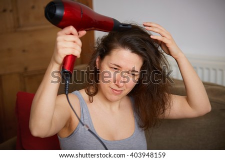 Young female dry her hair with red hair dryer
