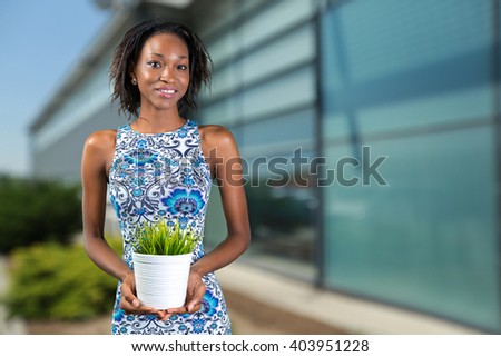 African woman holding plant in vase
