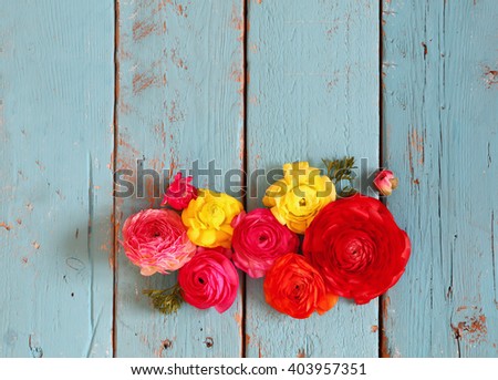 top view of colorful spring flowers on blue wooden background. vintage filtered