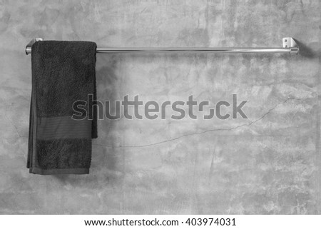 Stainless steel towel on grey cement wall with brown towel in bathroom