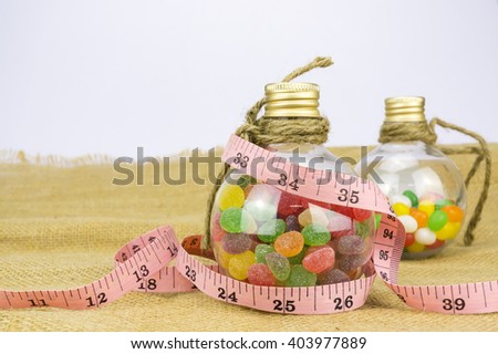 Colorful candies in bottles and tape measure with shallow depth of field (dof)-diet and healthy teeth concept