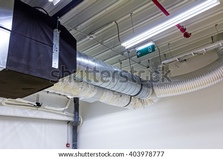 Ceiling with ventilation pipes for air condition and fire exit sign.