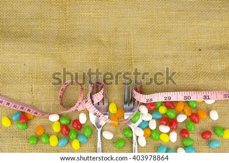 Colorful candies fork and tape measure with shallow depth of field (dof)-diet and healthy teeth concept