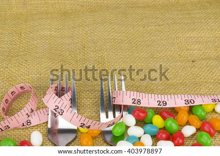 Colorful candies fork and tape measure with shallow depth of field (dof)-diet and healthy teeth concept
