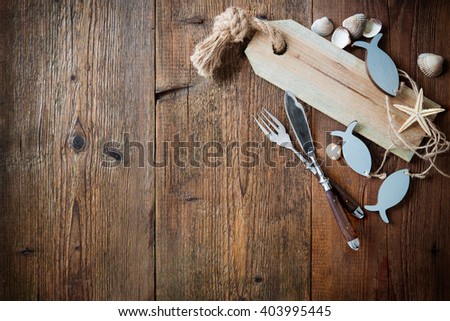 Fish cutlery tied with empty fish-shaped tag on wooden table with copy space. Menu card for restaurants