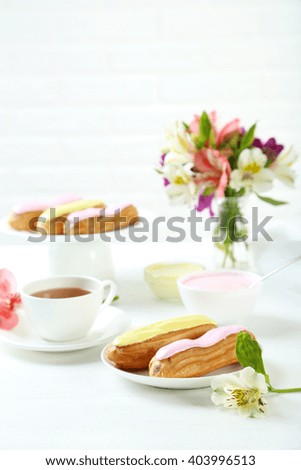 Eclairs with glaze on a white wooden table