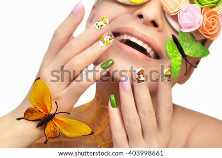 Multicolored manicure with pictures of butterflies on the nails and decorative rosettes on the eyes of a young woman.
