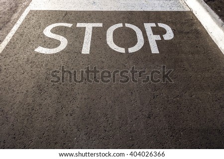 The word  'STOP'  painted in white on an asphalt road.