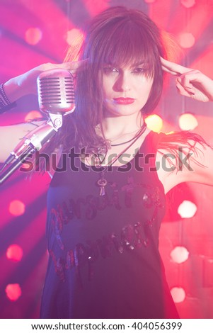 Beautiful blonde woman singer with a microphone, around smoke, color background