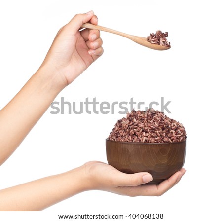 Hand holding spoon, eating brown rice isolated on white background