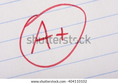 A plus (A+) grade written in red pen on notebook paper. Royalty-Free Stock Photo #404110102