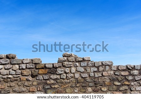 Old stone wall background under blue sky day.