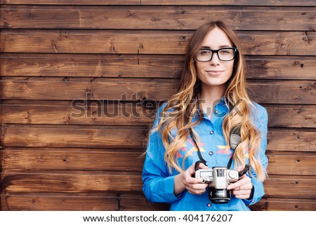 Happy young hipster woman in glasses holds retro photo camera