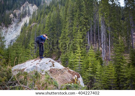 Nature photographer shooting a landscape with mountains and pine trees