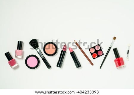 A row of beauty cometics that includes nail lacquer, lipstick, lip color, cheek blush, and brushes. Royalty-Free Stock Photo #404233093