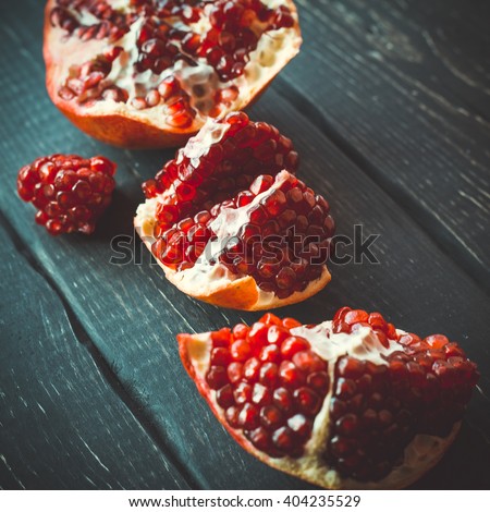 Halves of pomegranate on the black wooden table top