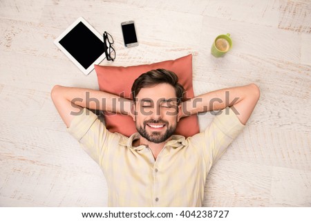 Portrait of happy man lying on floor and dreaming about smth Royalty-Free Stock Photo #404238727