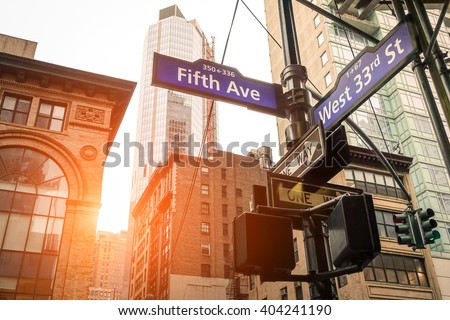 Street sign of Fifth Ave and West 33rd St at sunset in New York City - Urban road concept direction in Ny Manhattan downtown - American world famous capital destination on warm dramatic filtered look Royalty-Free Stock Photo #404241190
