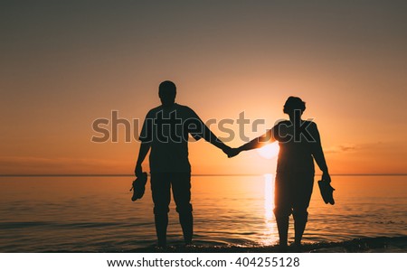 Silhouette of adult couple standing in the sea against a sunset. Evening photo.