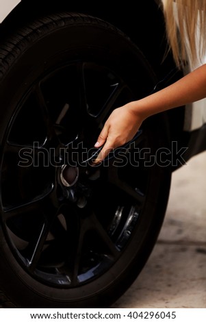 Woman is changing tire of car with wheel wrench