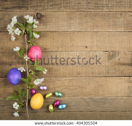 Bright, Colorful Easter Eggs and Candy on side of Rustic Country Wood Boards Background with blank room or space for copy, text, your words and with white spring flowers. Horizontal aerial top view