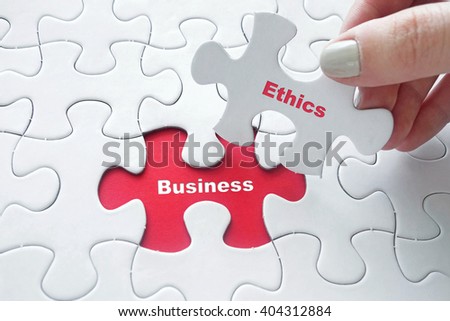 Close up of girl's hand placing the last jigsaw puzzle piece with word Business Ethics Royalty-Free Stock Photo #404312884