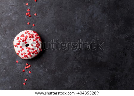 Donut with heart shaped decor on stone table. Top view with copy space