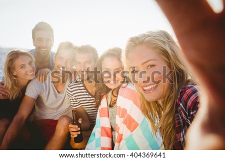 Happy friends taking selfie with smartphone on the beach