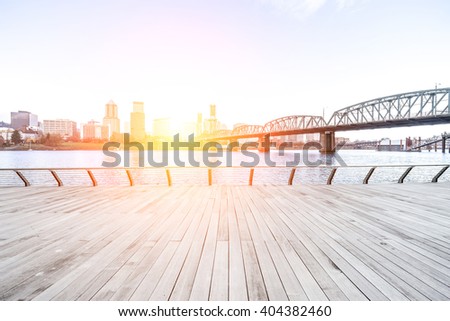 empty wood floor near steel bridge with cityscape and skyline of portland at sunrise