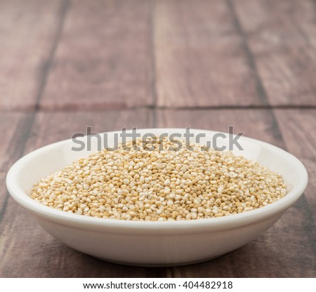 White quinoa grain in white bowl over wooden background