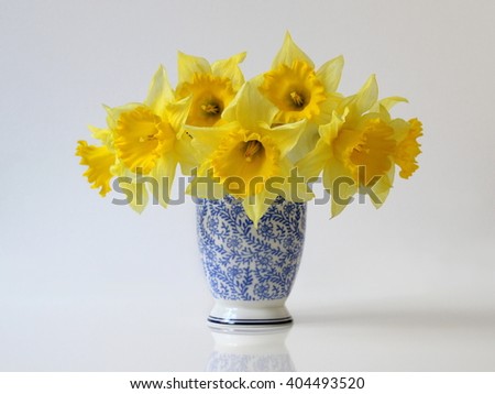 Bouquet of yellow daffodil flowers in a blue vase. Floral home decoration with bouquet of narcissus flowers in a vase. Flower fine art photography.
