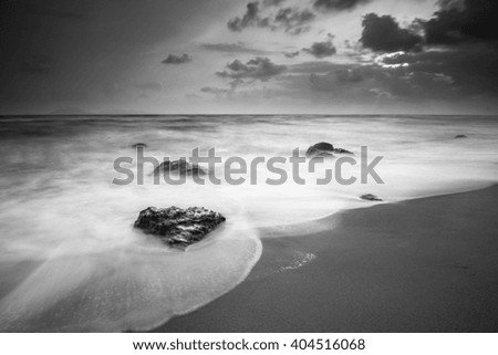 black & white daytime long exposure rocky seascape scene with stones and water