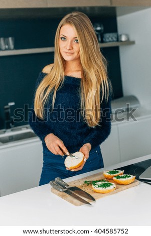 Young girl making sandwiches in the kitchen. Laptop on the kitchen table