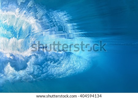 Underwater photo of ocean extreme wave breaking on tropical beach with spray, foam, ripples on water surface and bubbles pattern. Light blue color abstract background of clear sea surf with texture