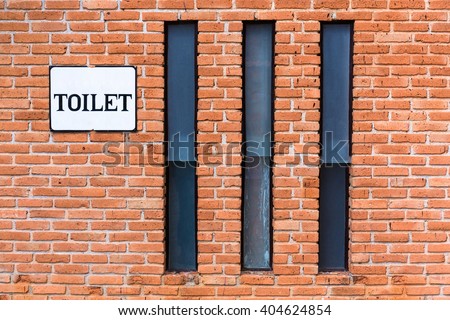 Brick wall with long windows and toilet sign, toilet exterior
