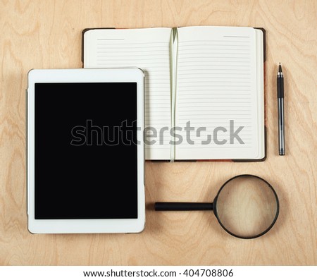 Flat lay of tablet computer, notebook, coffee cup  and pencil with blank center on wood background, top view