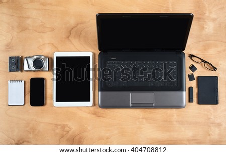 Flat lay of personal office accessories, laptop, notebook, coffee cup  and camera on wood background, top view