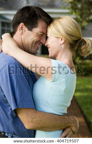 Couple standing on the garden path outside their new home, hugging