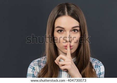 Nice girl holding her finger on the mouth