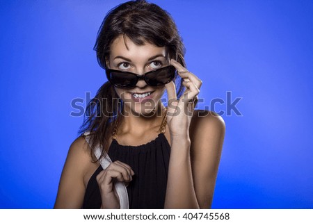 Female teen wearing sunglasses on vivid background lit with blue color gels