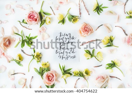 inspirational quote "doing what you like is freedom, liking what you do is happiness" written in calligraphy style on paper with pink roses and yellow flowers on white background. Flat lay, top view