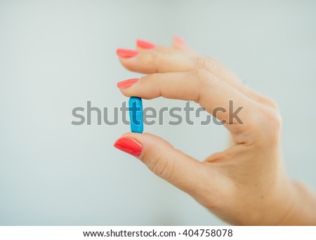 Women's fingers with pink manicure taking blue pills